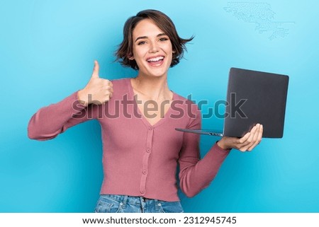Portrait of charming excited person hold netbook demonstrate thumb up feedback isolated on blue color background