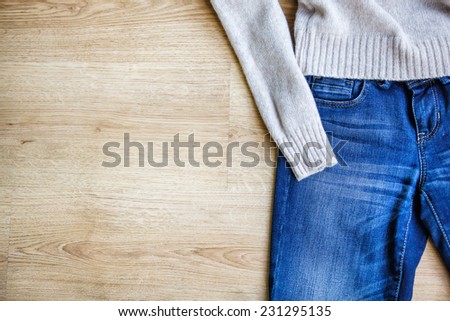 Jeans and woolen pullover on wooden background