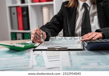 Woman wear black clasik suit filling 1040 blank US tax form, taxation concept, paperwork