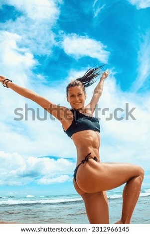colorful summer. happy emotional brunette girl in black swimsuit in jump with happy smile on the beach background with blue sky at sunny day. travel lifestyle concept, free space