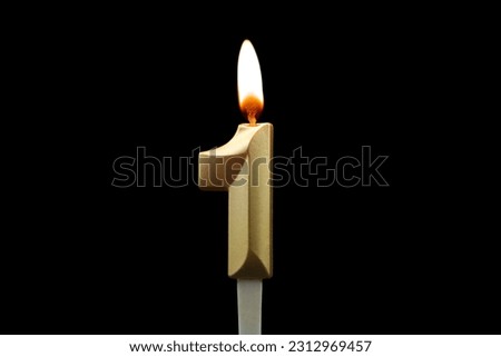 Burning gold birthday candle isolated on black background. Number 1. Royalty-Free Stock Photo #2312969457