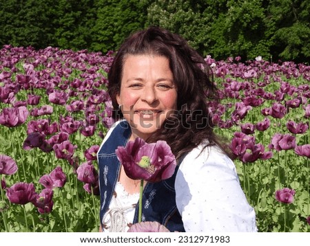 happy woman with field with purple poppy flowers