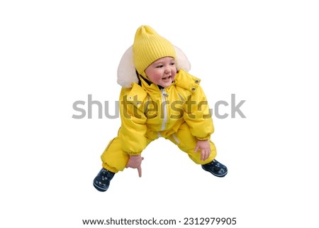 Happy toddler baby in winter clothes snowsuit isolated on a white background. A child in a warm yellow jumpsuit with a hood. Kid aged one year five months Royalty-Free Stock Photo #2312979905