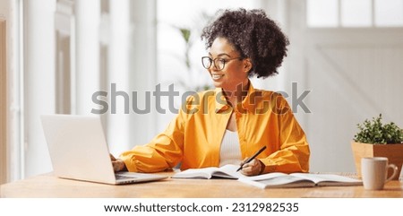 beautiful smiling african american woman  works remotely on laptop from home Royalty-Free Stock Photo #2312982535