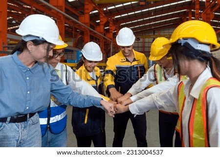 Group of male and female factory labor bumping fist together after finish meeting. Everyone wearing safety uniform and helmet. Workers working in the metal sheet factory. Royalty-Free Stock Photo #2313004537