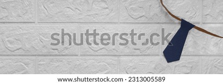 Business style banner with blue tie. Place for text. Necktie cut out of checkered paper on white brick wall background. Header for website, blog, article with concept of law, finance, Father's Day. Royalty-Free Stock Photo #2313005589
