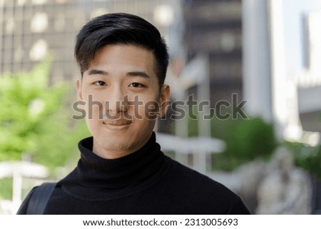 Closeup of handsome smiling asian man looking at camera, posing for picture. Attractive chinese male standing outdoors, advertisement