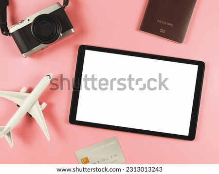 Top view or flat lay of digital tablet with blank white screen, airplane model, passport, credit card and digital camera isolated on pink background. travel planning concept.