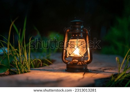 antique oil lamp on the old wooden floor in the forest at night camping atmosphere Royalty-Free Stock Photo #2313013281
