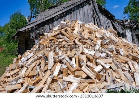 A large pile of chopped firewood on the ground. Firewood for heating in fireplaces and stoves.