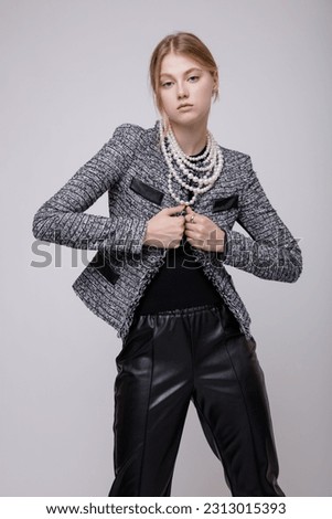 Fashion photo of a beautiful elegant young woman in a pretty suit, black leather pants, trousers, gray jacket, blazer, top posing on white background. Studio Shot, portrait. Slim figure. Blonde