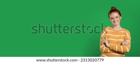 Chroma key compositing. Happy young woman with red hair against green screen