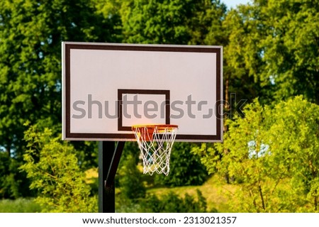 Basketball basket in an outdoor court with a green trees on background