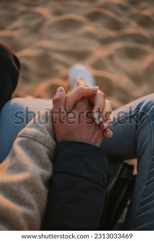 Couple's hands in love on the beach at the sunset golden hour