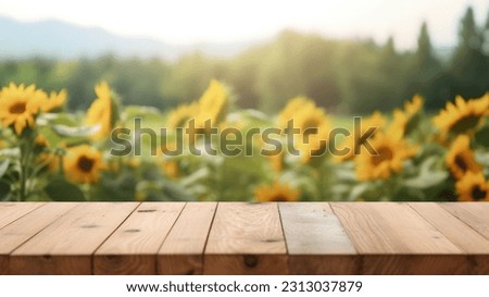 The empty wooden table top with blur background of sunflower field. Exuberant image.