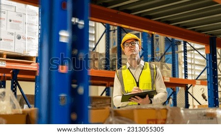 Man warehouse worker with a tablet.Retail Warehouse full of Shelves with Goods in Cardboard Boxes.Worker with scanner making review of goods in warehouse.Product Distribution Delivery Center.
