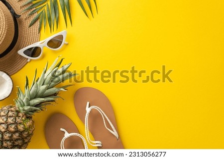Immerse yourself in the summer relaxation with this top view flat lay. With a sunhat, palm leaves, flip-flops, coco nut and a pineapple on a bright yellow background, the empty space for text Royalty-Free Stock Photo #2313056277