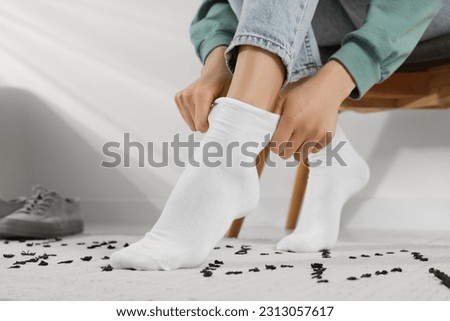 Woman putting on white socks at home, closeup Royalty-Free Stock Photo #2313057617