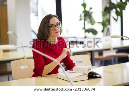 Young woman  in library hold pencil at hand