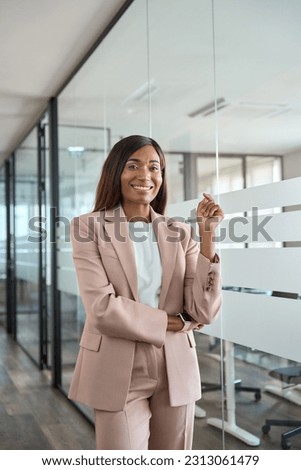 Confident happy young professional business woman ceo corporate leader, female African American lawyer or executive manager wearing suit standing in office at glass wall, vertical portrait. Royalty-Free Stock Photo #2313061479