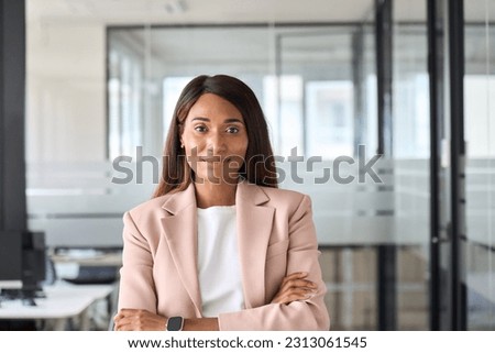 Confident smiling young professional business woman ceo corporate leader, female African American lawyer or leader manager wearing suit standing arms crossed in office, headshot portrait. Royalty-Free Stock Photo #2313061545