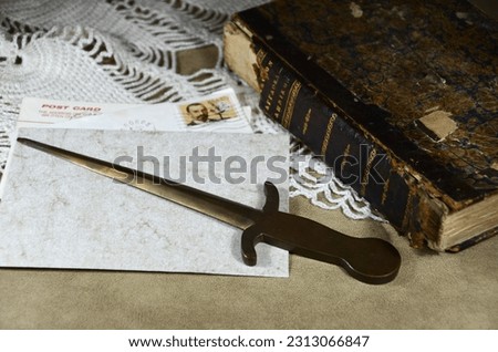 Vintage handmade letter opener with postcard and old book Royalty-Free Stock Photo #2313066847