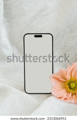 Flatlay of blank screen mobile phone and poppy flower. Copy space mockup template