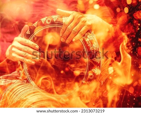 Shaman woman playing on drum on fire background.