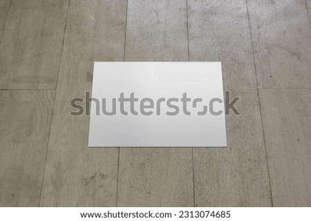 A white blank a4 paper page is isolated on the textured wooden floor, for showcase presentation or corporate document mockup.