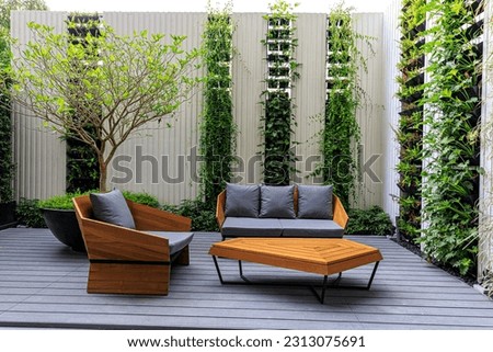 two stylish wooden chairs with cushions and a small wooden table at a balcony of a room in a resort, surrounded by garden Royalty-Free Stock Photo #2313075691