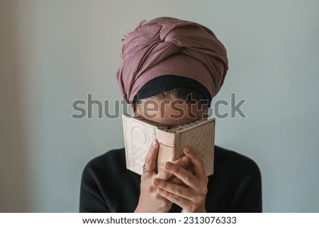 Young jewish woman with a covered head prays with a siddur (jewish prayer book) in her hands, covered his face with her hands (66) Royalty-Free Stock Photo #2313076333