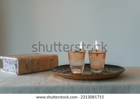 On the table are two candles lit on shabbat and a siddur (religious jewish prayer book). Jewish holidays and traditions (70) Royalty-Free Stock Photo #2313081715