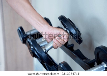 Dumbbells are in the hands that are raised in the gym.             Royalty-Free Stock Photo #2313084711