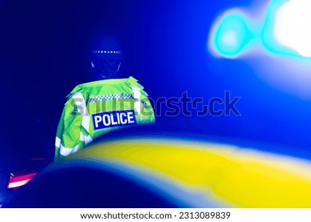 Police Officer at nighttime scene with Blue emergency lights Royalty-Free Stock Photo #2313089839