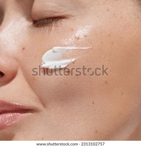 Cream smear. Beauty close up portrait of young woman with a healthy skin is applying a facial skincare product. Face  daily care routine  Royalty-Free Stock Photo #2313102757