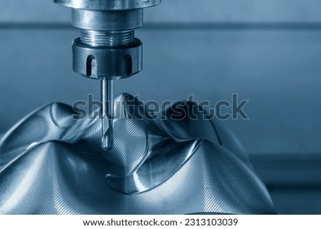 The CNC milling machine cutting injection mold part by solid ball end mill tool in the light blue scene. The mold parts cutting process by machining center with solid ball end mill. Royalty-Free Stock Photo #2313103039