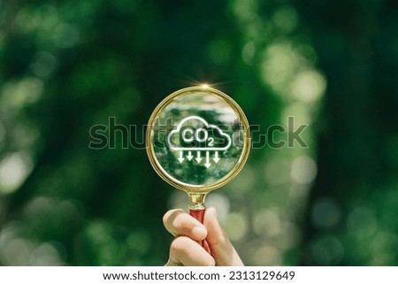 hand holding magnifying glass with CO2 reduction icon inside.A clean and friendly environment without carbon dioxide emissions.carbon credit to limit global warming from climate change.carbon neutral. Royalty-Free Stock Photo #2313129649