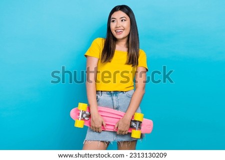 Photo of cheerful nice person hold skateboard look empty space isolated on blue color background