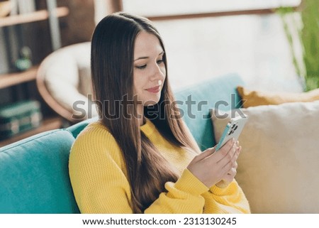 Photo of lovely peaceful lady sitting couch hold use smart phone eshopping chatting write comment apartment inside