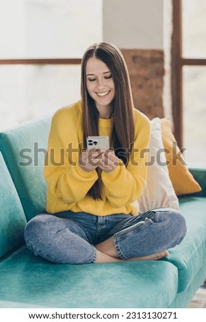 Full size vertical photo of positive peaceful person sit comfy couch use smart phone communicate write blog post flat indoors
