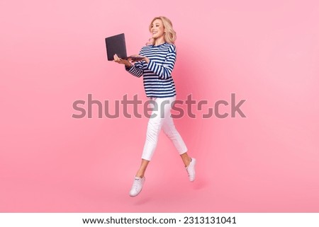 Full length photo of excited sweet woman dressed striped shirt jumping high read email modern device isolated pink color background