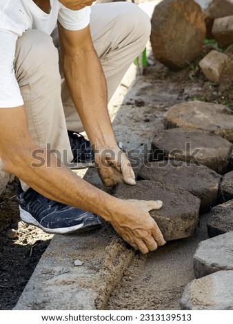 Hands of workman make it fit and to place stone pavers in a row. Construction site of pavement octagon bricks road. Installation or renovation repair. Lays out paving slabs. Selective focus on hands.