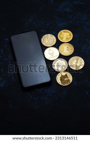 Various cryptocurrencies next to a smartphone on a dark background