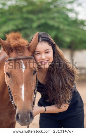 Portrait of smiling girl with a chestnut pony looking at the camera