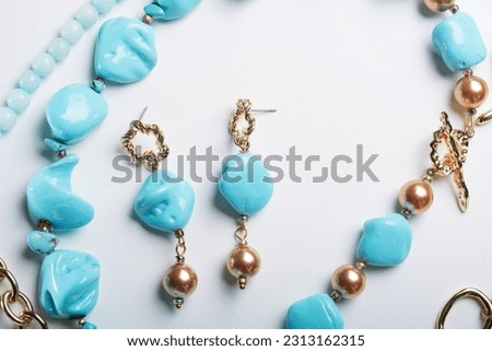 author collection jewelry with azure gemstones, pearls and chain demonstrated at white  background.  fashion and jewelry concept. flat lay