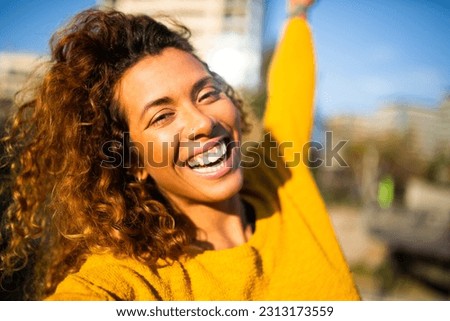 Selfie portrait of laughing young latin woman outside in the city