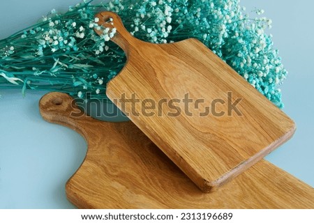  Two wooden cutting boards made of solid oak next to a green dried flower - gypsophila on a light pastel background. Interior of rural authentic kitchen. Natural lighting. Photo 