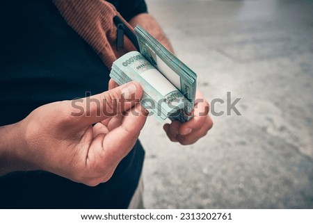 Man holds stack of Lebanese liras equivalent to one hundred dollars. Hyperinflation in Lebanon. Devaluation of Lebanese currency. Hands of man counting Lebanese pounds Royalty-Free Stock Photo #2313202761