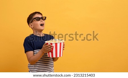 Kids cinema. Shocked little boy with popcorn in 3d glasses looking at copy space and wondering on yellow background, kid amazed viewer watching movie, isolated on yellow background, web-banner