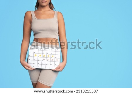 Serious millennial caucasian slim woman in sportswear hold calendar, ready for workout, isolated on blue studio background, cropped. Sports and periods, weight loss and body care, time management Royalty-Free Stock Photo #2313215537